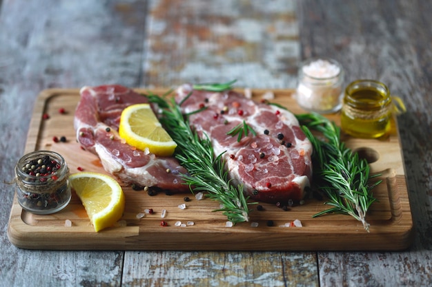 Bistecche di carne cruda su un tagliere. carni fresche con rosmarino e spezie.