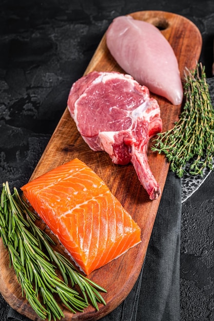 Raw meat steaks fish salmon beef veal and turkey black\
background top view