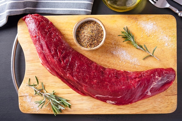 Raw meat tenderloin on wooden cutting board with spices Top view Uncooked food