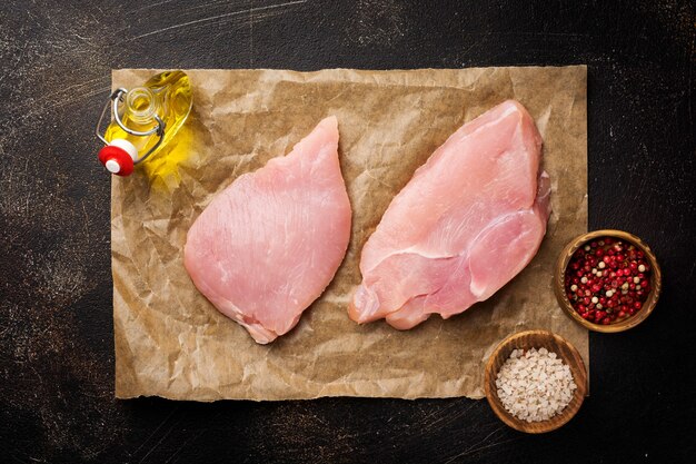 Raw meat of turkey steak on dark old table. Top view.