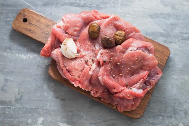 Raw meat of turkey with chestnuts and garlic on wooden board