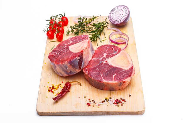 сырое мясо, телятина оссобуко, говядина на кости, на деревянной разделочной доске, на белом изолированном фоне