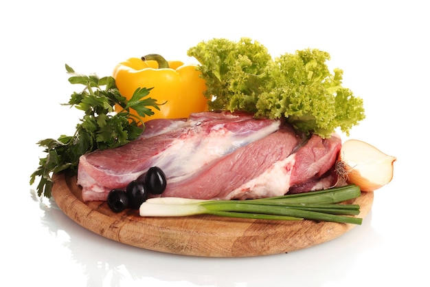 Raw meat and vegetables on a wooden board isolated on white