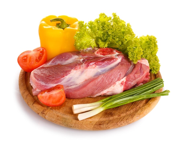 Raw meat and vegetables on a wooden board isolated on white