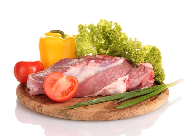 Raw meat and vegetables on a wooden board isolated on white