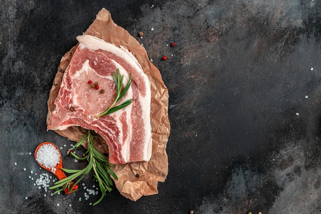 Raw meat with herbs and spices on dark background Raw Pork meat chop steak Restaurant menu dieting cookbook recipe Top view