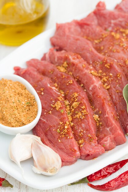 Raw meat with herbs on white dish on wooden surface