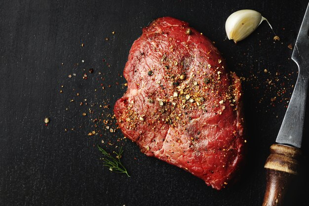 Raw meat with spices on dark table. Ready for cooking.