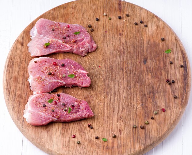 Raw meat on a wooden cutting board with spices