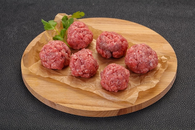 Raw meatball over wooden background