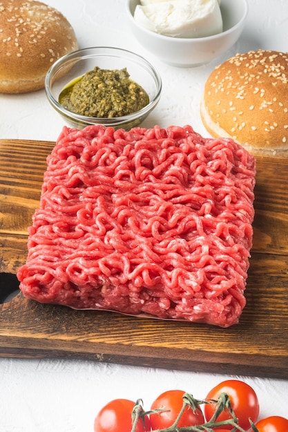 Raw meatballs burger or sandwich ingredients with sesame buns on wooden cutting board on white stone background