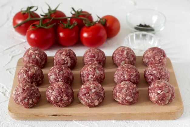 Raw meatballs, tomatoes and spices. rustic style.