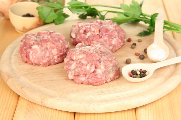 Raw meatballs with spices on wooden table