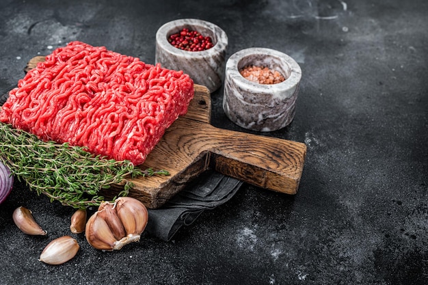 Raw Mince, minced Ground beef meat on a cutting board. Black background. Top view. Copy space.