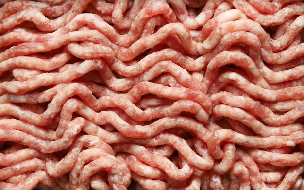 Raw minced beef and pork chopped in meat grinder, close-up food background