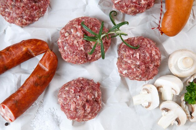 Raw minced hamburger meat and sausage with herb and spice prepared for grilling