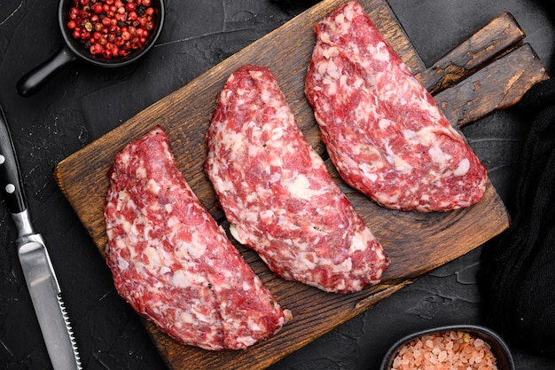 Raw Minced Meat Cutlets. Fresh Minced Beef Pork Steak Burgers set, on black dark stone table background, top view flat lay