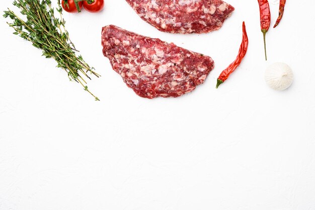 生のひき肉のカツレツ。新鮮な牛挽肉のポークステーキバーガーセット、白い石のテーブルの背景、上面図フラットレイ、テキスト用のコピースペース