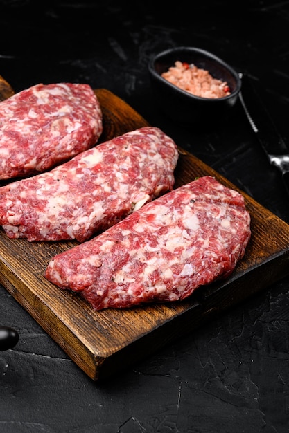 Raw Minced Meat Cutlets set on black dark stone table background