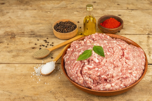 Raw minced meat. Ground pork with spices, cooking oil. Old wooden table, copy space