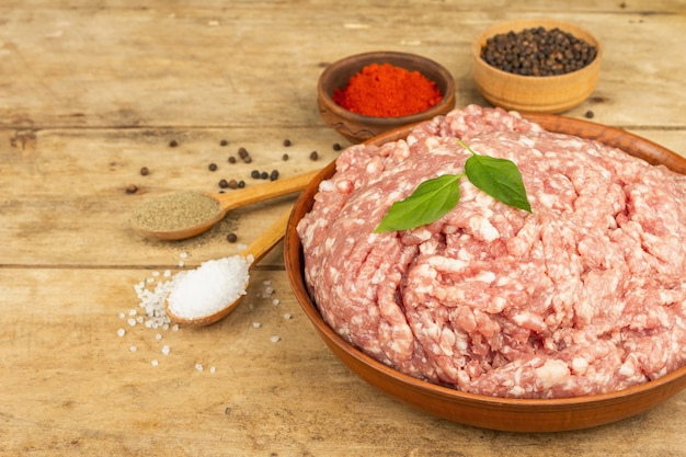 Raw minced meat. Ground pork with spices, cooking oil. Old wooden table, copy space