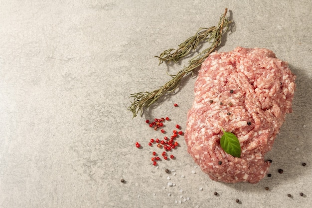 Raw minced pork. Fresh ground meat with spices and onion. Grey stone concrete background, top view