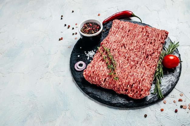 Raw minced pork with spices on board light background. place for text, top view