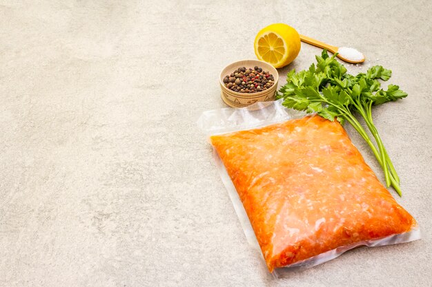 Raw minced red fish (stuffing) on a stone surface. Ingredient for making fish-balls, casseroles, terrine, pate. Spices, salt, parsley, lemon. On a stone surface, copy space.