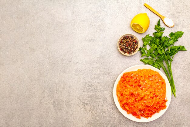 Raw minced red fish (stuffing) on a stone surface. Ingredient for making fish-balls, casseroles, terrine, pate. Spices, salt, parsley, lemon. On a stone surface, top view, copy space.