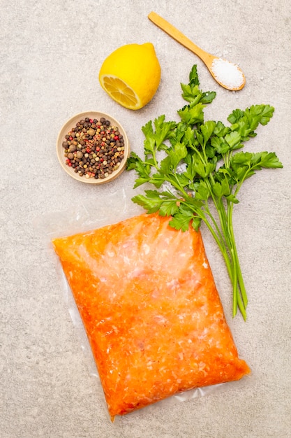 Raw minced red fish (stuffing) on a stone surface. Ingredient for making fish-balls, casseroles, terrine, pate. Spices, salt, parsley, lemon. On a stone surface, top view.