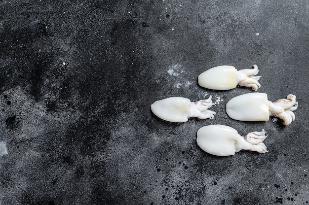 Raw mini cuttlefish on the table. Black background