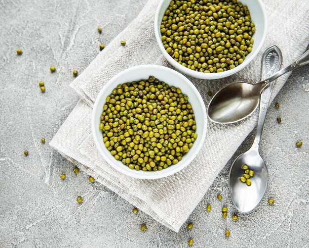 Raw mung beans in the  bowls on a grey concrete background