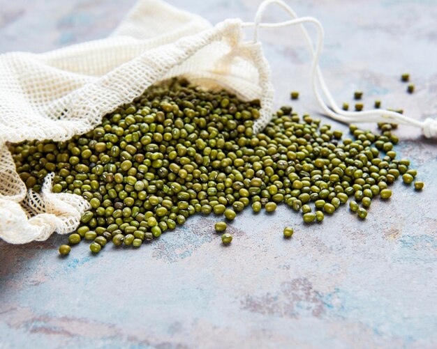 Raw mung beans in the cotton bag on a grey concrete background