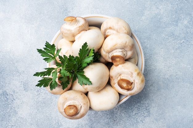 Raw mushrooms champignons in a plate