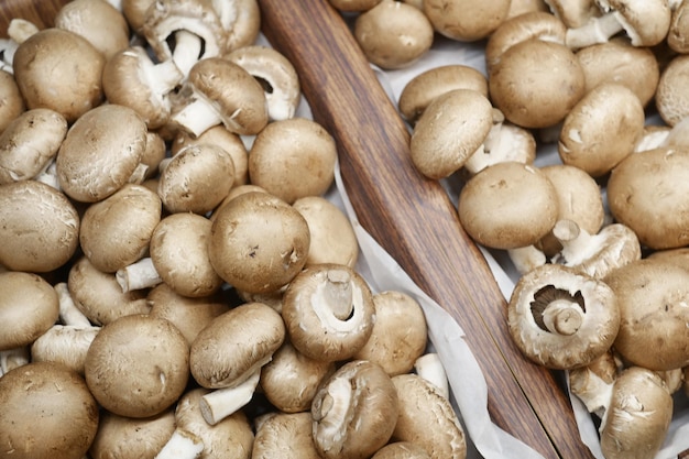 Raw mushrooms champignons in a wooden bowl