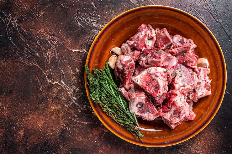 Photo raw mutton meat diced for goulash or stew with bone on a rustic plate. dark 