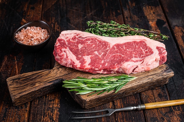 Raw new york strip beef steak or striploin on a wooden board