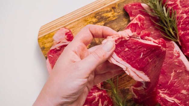 Raw New York strip steaks on a wood cutting board.