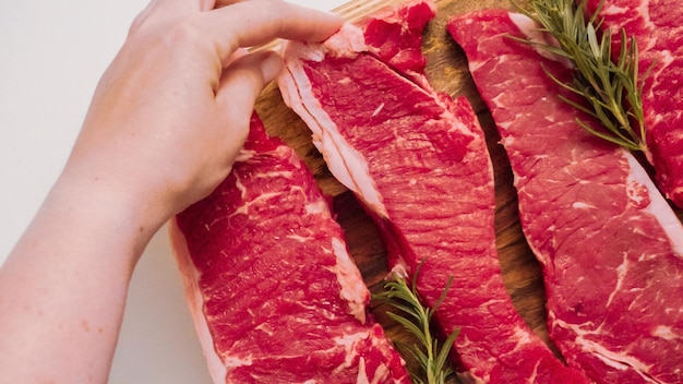 Raw New York strip steaks on a wood cutting board.