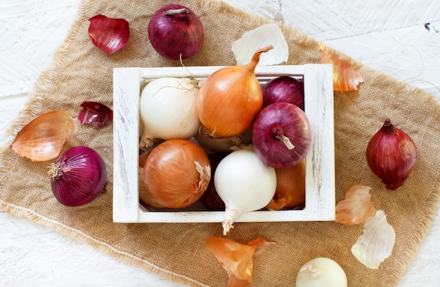 Raw onions in a box on a wooden table