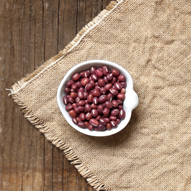 Raw Organic azuki beans in a bowl top view on a wooden table on burlap