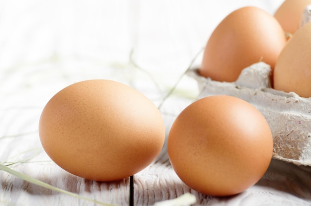 Raw organic brown chicken eggs in eco friendly paper carton on white kitchen wooden table