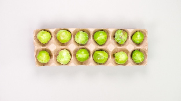 Photo raw organic brussel sprouts in brown egg container on grey background top view