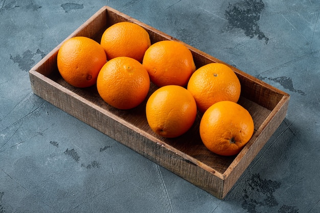 Raw Organic Cara Navel Oranges set, in wooden box, on gray stone table