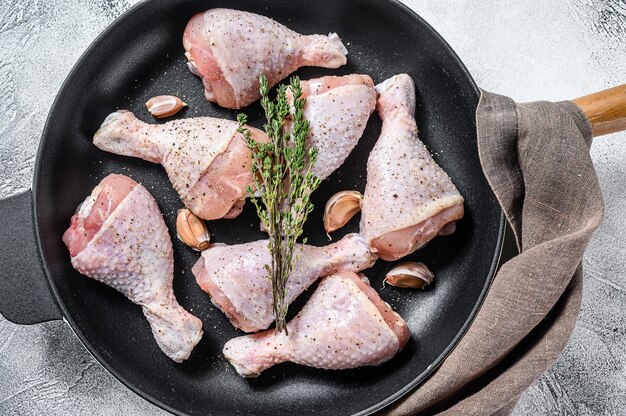 Raw organic chicken legs with spices and garlic ready to cook in a pan