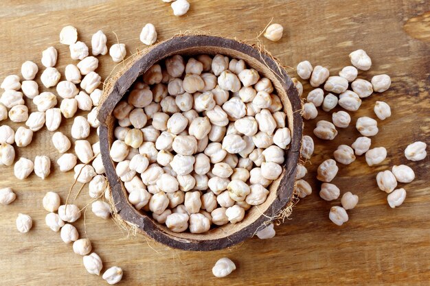 Raw organic chickpeas grains in bowl over rustic wooden table Top view