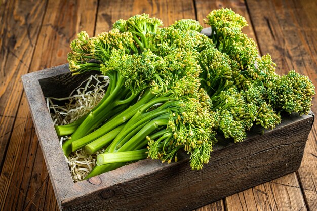 Raw Organic Fresh Broccolini Vegetable in a wooden box Wooden background Top view