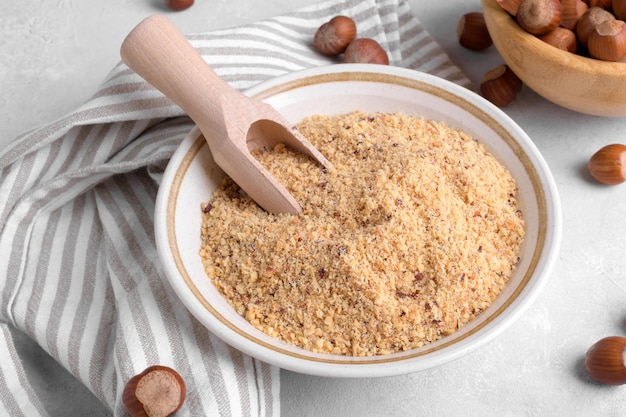 Raw Organic Ground Hazelnut Flour in a Bowl with whole nuts on grey stone background Alternative nut flour