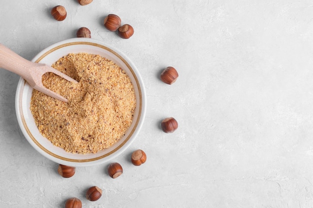 Raw Organic Ground Hazelnut Flour in a Bowl with whole nuts on grey stone background Alternative nut flour