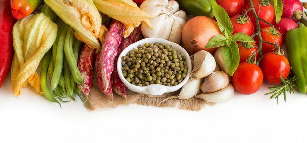 Raw organic mung beans in a bowl and raw vegetables